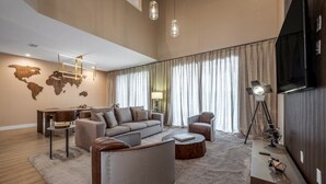 Un soggiorno moderno con un divano grande, un tavolino da caffè e una TV. Si vede una mappa del mondo sulla parete e una lampada su un tavolino.