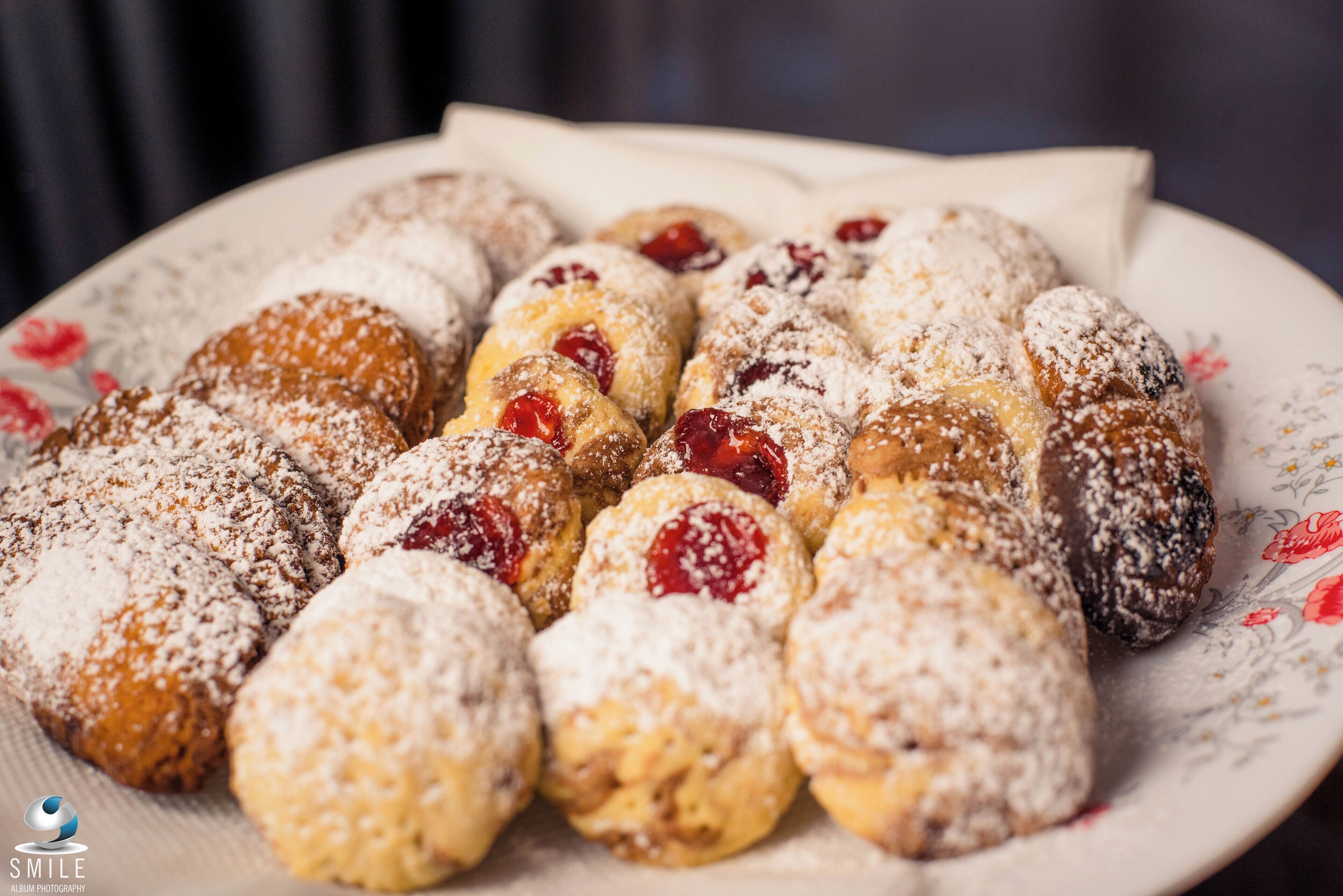 Un plato de pasteles variados espolvoreados con azúcar glas y rellenos de fruta.