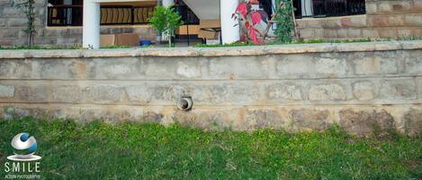 Una casa de dos pisos con un balcón, una escalera y un muro de piedra.