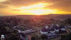 A village with traditional round-roofed buildings, surrounded by hills and a sunset in the background. - Turaco Intercounty Resort Limited  (Kisumu)