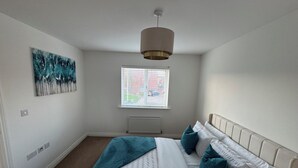 Un dormitorio con una cama, una ventana con persianas, un radiador y una lámpara en el techo.