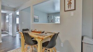 A dining area with a wooden table, two chairs, and a rug. A large mirror hangs on the wall above the table. - Jelinek Hideaway Unit 5 - Modern 2BR Apartment (Schofield)