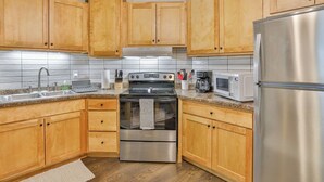 A kitchen with wooden cabinets, stainless steel appliances, a microwave, and a sink. - Jelinek Hideaway Unit 5 - Modern 2BR Apartment (Schofield)
