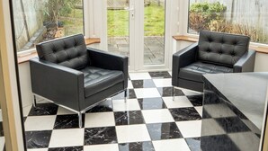 A conservatory with a checkered floor, two black leather sofas, and a glass door leading outside. - 3 Merlin Gardens Modern 2 Bed Bromley House (Bromley)
