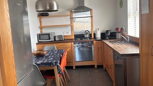 Una cocina compacta equipada con refrigerador, microondas, tostadora, hervidor y lavaplatos.