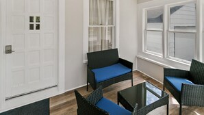 A room with a white door, two wicker chairs with blue cushions, a glass table, and a window with blinds. - New updated home w/ porch and Fenced yard in DT Libertyville Near Naval Base (Libertyville)