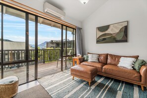 A spacious living room with a leather sofa, a large window, and a view of the outdoors.