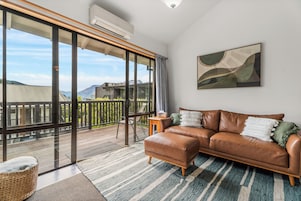 A spacious living room with a leather sofa, a large window, and a view of the outdoors.