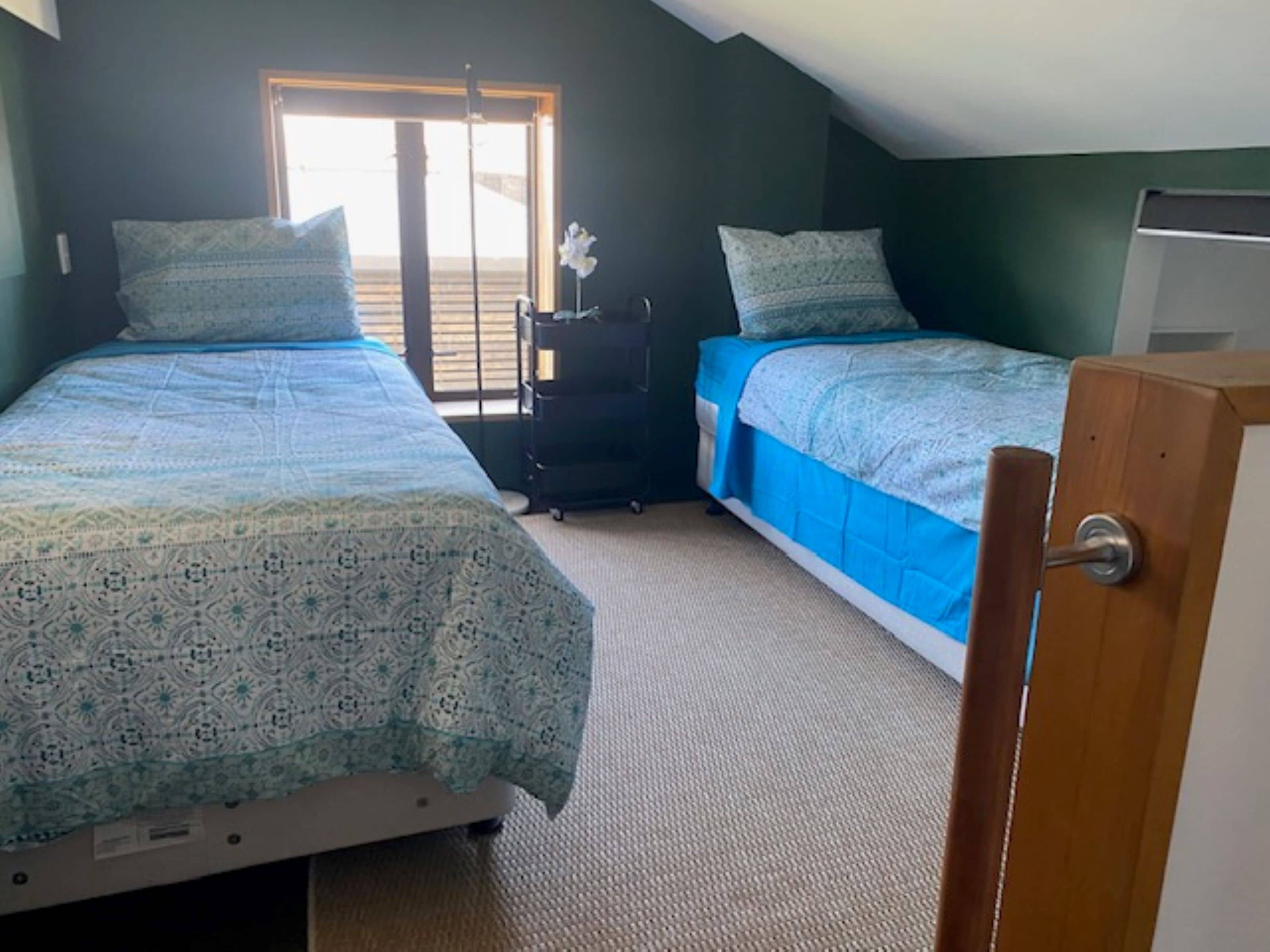 Un dormitorio con dos camas, un aparador y una puerta.