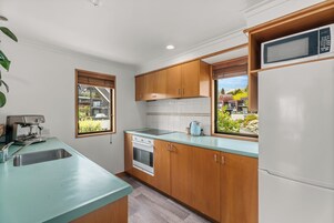 A kitchen with wooden cabinets, a stainless steel sink, a built-in oven, and a microwave.