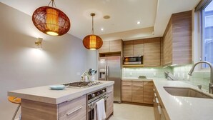 Una cocina moderna con gabinetes de madera, electrodomésticos de acero inoxidable e iluminación colgante.