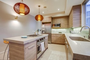 Una cocina moderna con gabinetes de madera, electrodomésticos de acero inoxidable e iluminación colgante.