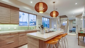 Una cocina moderna con una isla grande, armarios de madera e iluminación colgante.