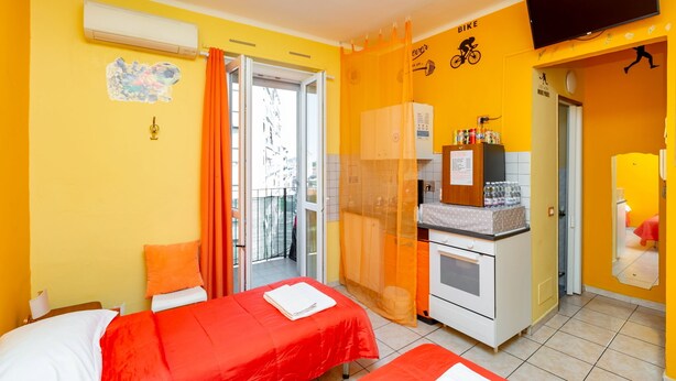 A hotel room with two beds, an air conditioning unit, a television, a kitchenette, and a balcony with a view. - Sports Cave (Torino)