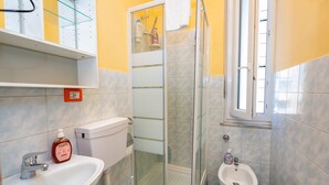 A bathroom with a sink, toilet, bidet, and a glass-enclosed shower. - Sports Cave (Torino)