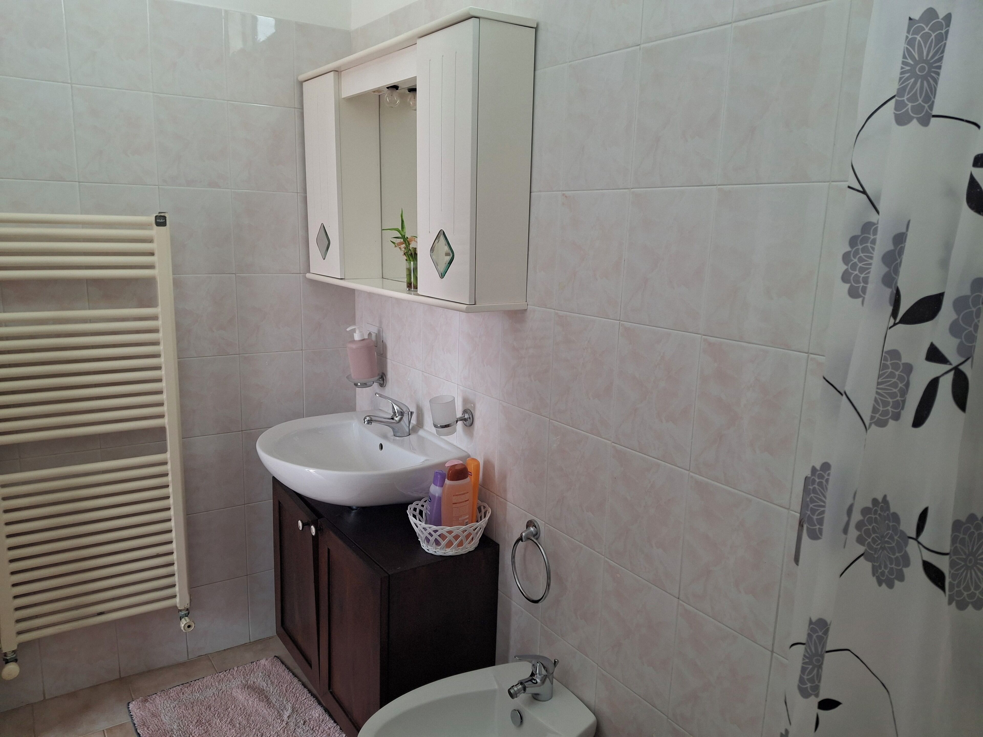 Une salle de bain avec un lavabo blanc, un meuble en bois foncé et un miroir au-dessus.