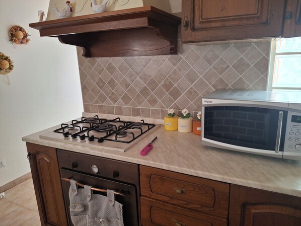 A kitchen with a gas stove, a microwave, and wooden cabinets.