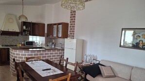 Una cocina con salpicadero de ladrillo, armarios de madera, una mesa de comedor con sillas, un refrigerador y un sofá.