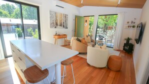 A modern kitchen with a large island, wooden flooring, and a dining area with a sofa and chairs. - The Rocks - Olive Retreat (Bright)