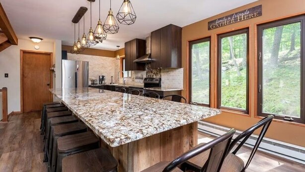 A kitchen with a large island, bar stools, and a sign that reads "family & friends gather here". - Rustic Ski Retreat! 2 min. walk to Ski Slopes, 6TVs, Linens, Wi-Fi, A/C, Firepit (bushkill)