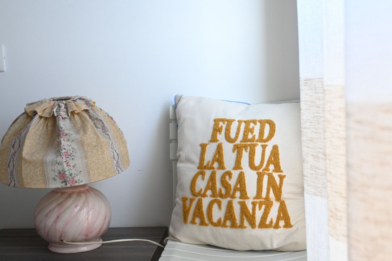 Abajur com cúpula florida e travesseiro com texto.