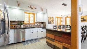 A modern kitchen with white cabinets, a wooden countertop, and a built-in dishwasher. - Beautiful Modern Lodge! Pool Table,8 TVs Wi-Fi, Linen provided, Central AC (Saw Creek)
