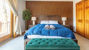 A neatly made bed with blue bedding, two bedside lamps, and a green ottoman. - Beautiful Modern Lodge! Pool Table,8 TVs Wi-Fi, Linen provided, Central AC (Saw Creek)