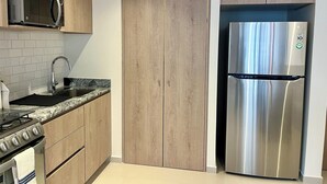 A modern kitchen with wooden cabinets, a stainless steel refrigerator, a microwave, and a gas stove. - Beautiful loft in amazing Guadalajara with AC, WiFi, fitness room, and workspace (Guadalajara)