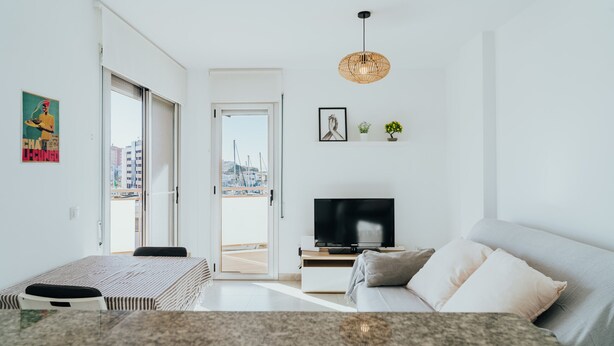 A modern living room with a TV, sofa, and dining area. - WELCS APARTAMENTO 206 EMP cerca del mar (Rosas / Roses)