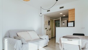 A modern living room with a sofa, a dining table, and a kitchen in the background. - WELCS APARTAMENTO 206 EMP cerca del mar (Rosas / Roses)