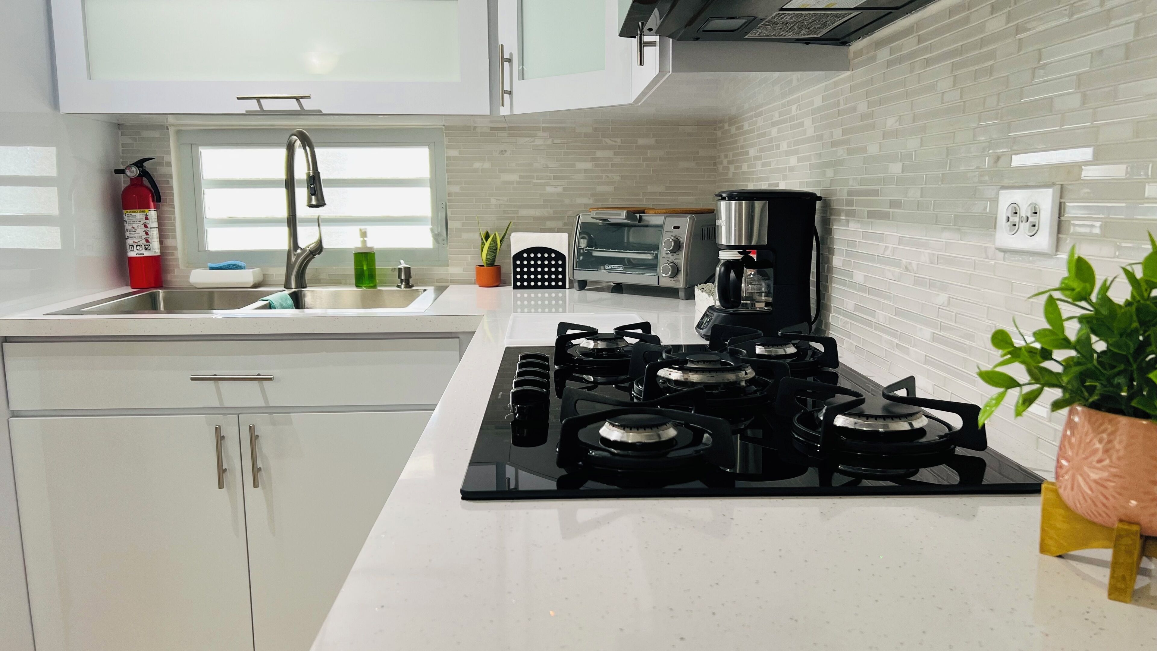 A modern kitchen with a gas stove, a coffee maker, and a toaster.