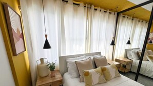 A bedroom with a bed, bedside tables, a mirror, and curtains.