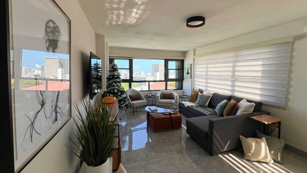 A modern living room with a large window, a Christmas tree, and a sofa.