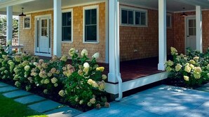 Une maison à deux étages, dotée d’un porche couvert et d’une façade en briques.