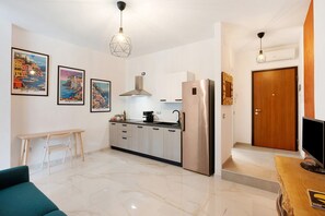 A modern kitchen with a stainless steel refrigerator, a wooden dining table, and a sofa. - Apartment 'Sempresole In Piazzetta' with Mountain View, Wi-Fi and Air Conditioning (Salerno)