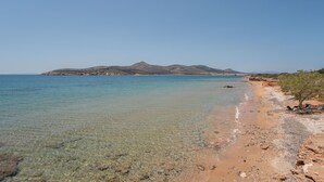 A beach with clear water, rocky shore, and distant mountains. - Apartment 'Blue Dolphin Family Pool' with Sea View, Wi-Fi and Air Conditioning (Ag. Georgios)