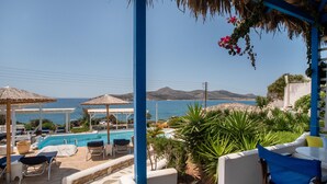 A poolside area with lounge chairs, a swimming pool, and a view of the sea and mountains. - Apartment 'Blue Dolphin Family Pool' with Sea View, Wi-Fi and Air Conditioning (Ag. Georgios)