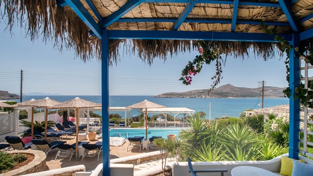 A poolside area with lounge chairs, a pool, and a view of the sea. - Apartment 'Blue Dolphin Family Pool' with Sea View, Wi-Fi and Air Conditioning (Ag. Georgios)