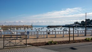A coastal view with boats, a white fence, and a lighthouse.