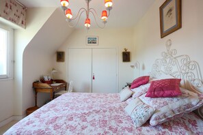 Un dormitorio con cama, escritorio, silla, armario y candelabro.