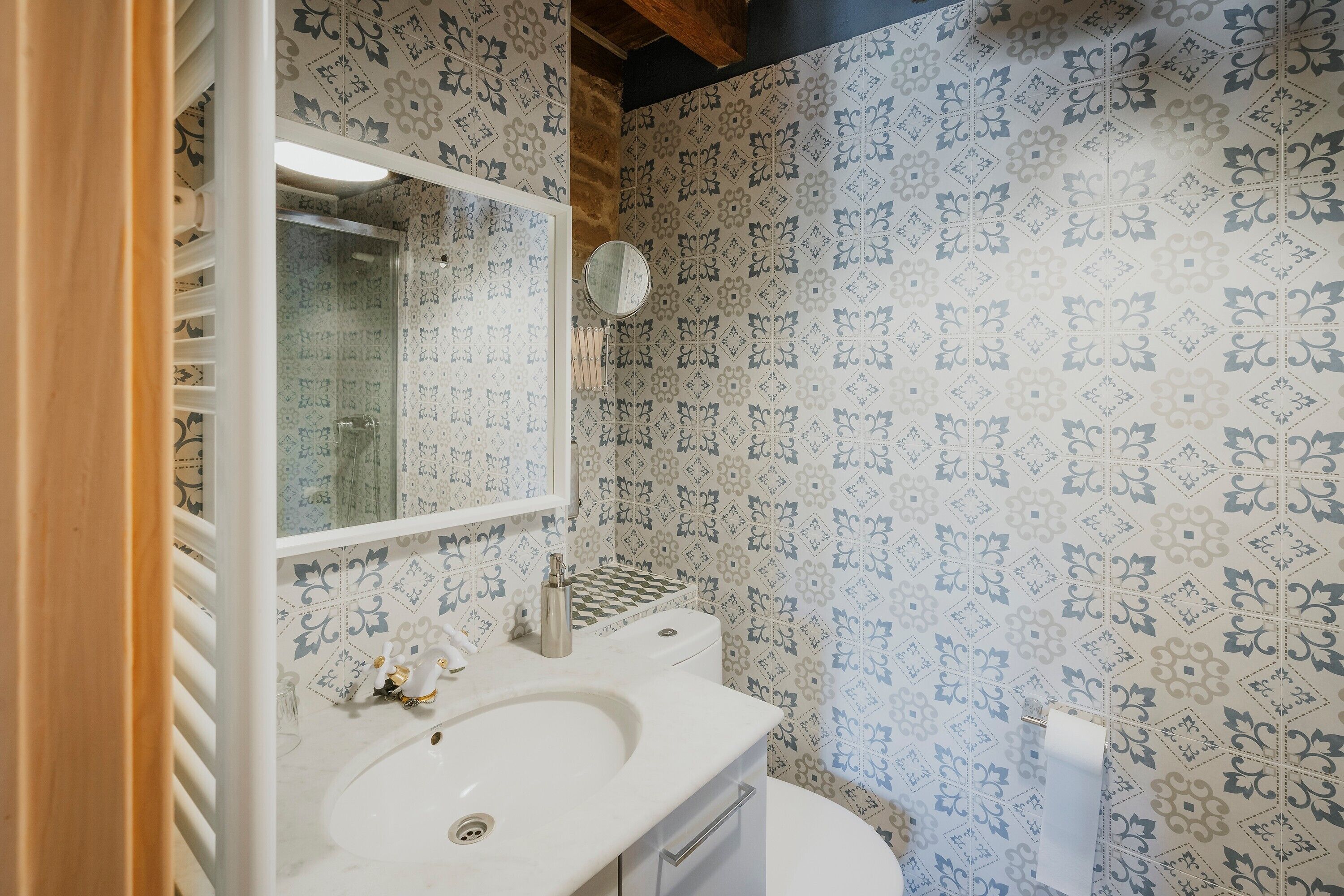 Une salle de bain avec un papier peint à motifs, un lavabo, un miroir et des toilettes.