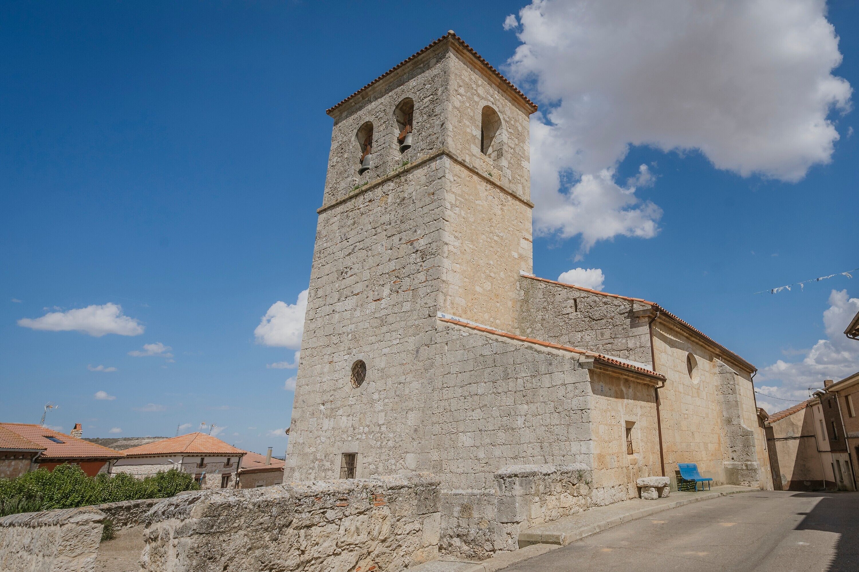 Una torre de piedra con ventanas de arco y una campana, parte de un edificio histórico con tejado de tejas.