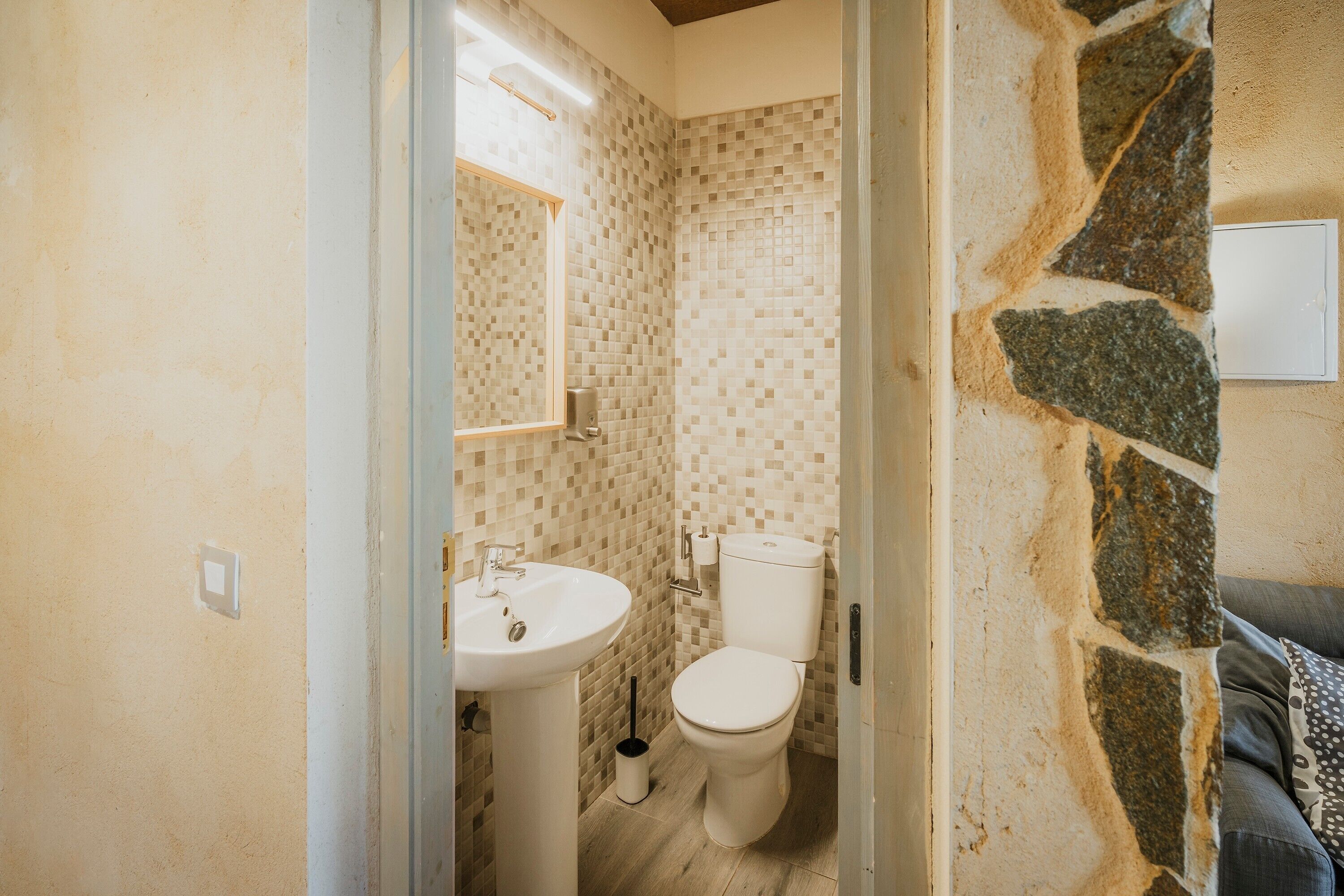 Un baño con pared de azulejos, un lavabo e inodoro.