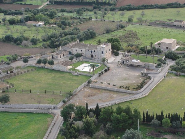 A rural estate with stone buildings, a fenced courtyard, and surrounding fields.