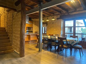 Ein rustikales Interieur mit einer Holztreppe, Steinwänden, einer Küchenzeile und einem Essbereich mit Stühlen und einem Tisch.