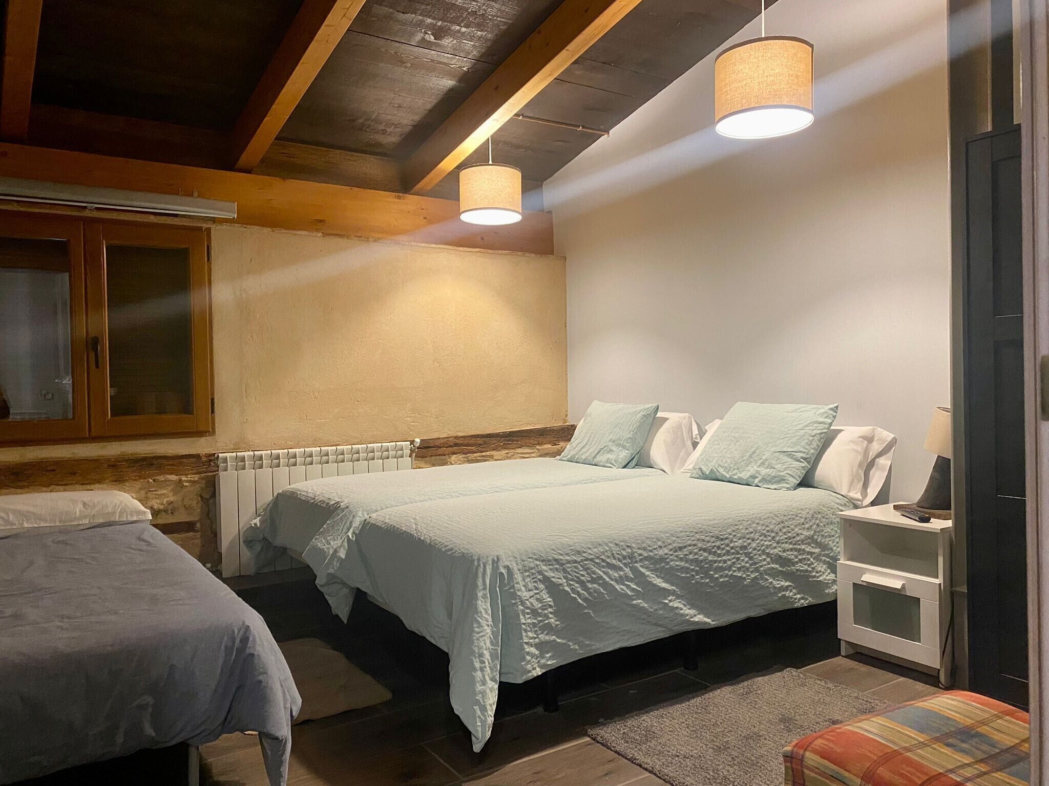 A bedroom with a bed, bedside table, lamp, and a window with curtains.