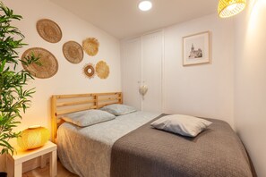 Un dormitorio con cama, mesita de noche, decoración en la pared y un cuadro enmarcado.