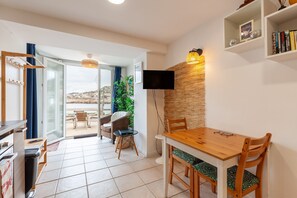 Una sala moderna con una mesa de comedor de madera, un televisor de pantalla plana montado en la pared y un balcón con vistas.