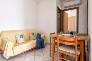 Una habitación con un sofá amarillo, una mesa de comedor de madera y un espejo.