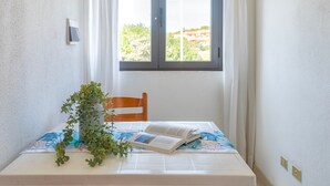 Una habitación con ventana, una silla, una mesa con un libro y una planta.